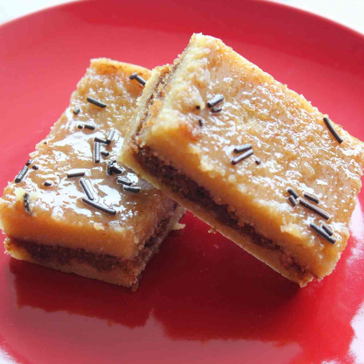 A photo of two brown sugar cinnamon bars layered on top of one another on a red plate.
